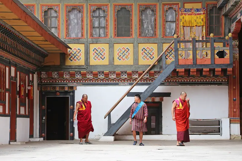 Monks crossing a painted dzong courtyard in Thimphu